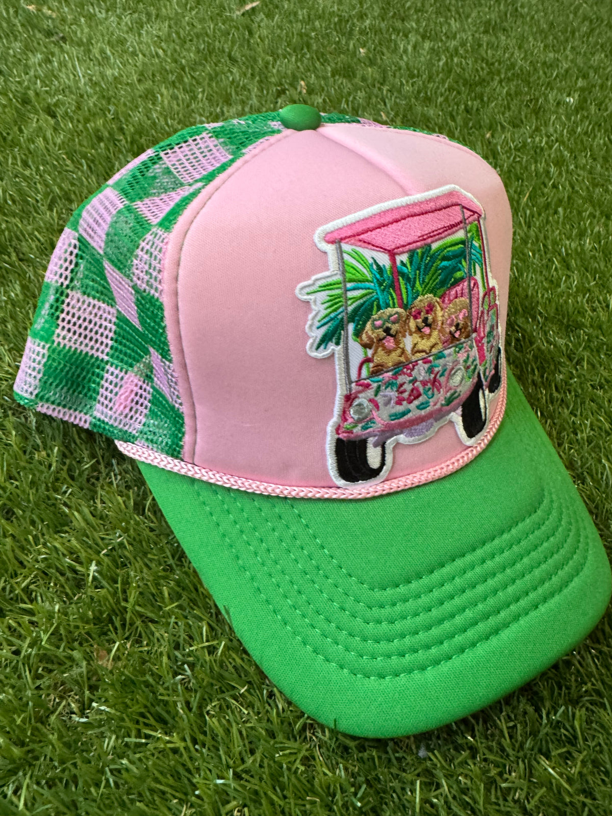 Dogs on a golf cart on pink/green mesh trucker hat