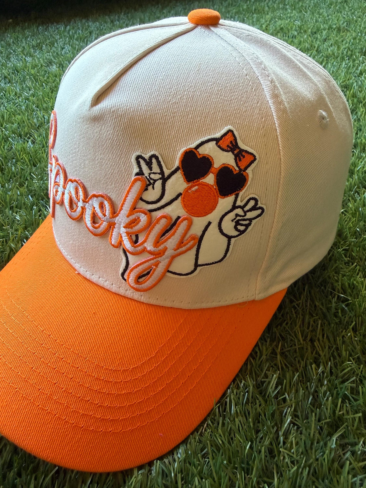 Spooky embroidered patch with ghost blowing a bubble on custom canvas trucker hat with orange brim