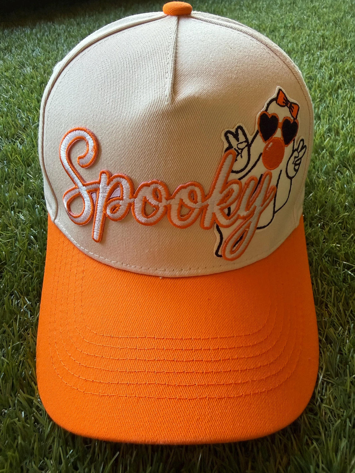 Spooky embroidered patch with ghost blowing a bubble on custom canvas trucker hat with orange brim
