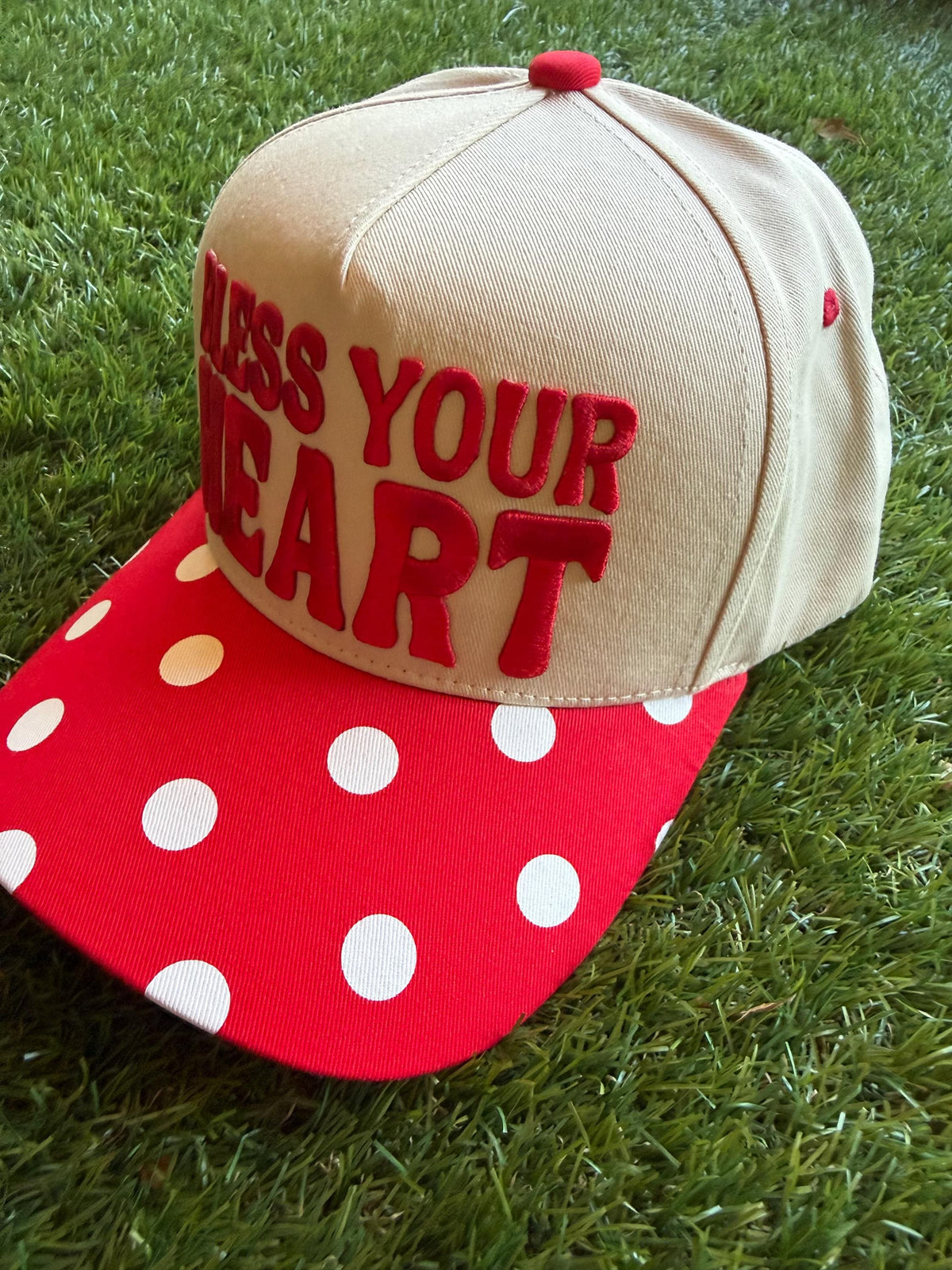 BLESS YOUR HEART embroidered word patch on a custom canvas trucker hat with red and white polka dot brim