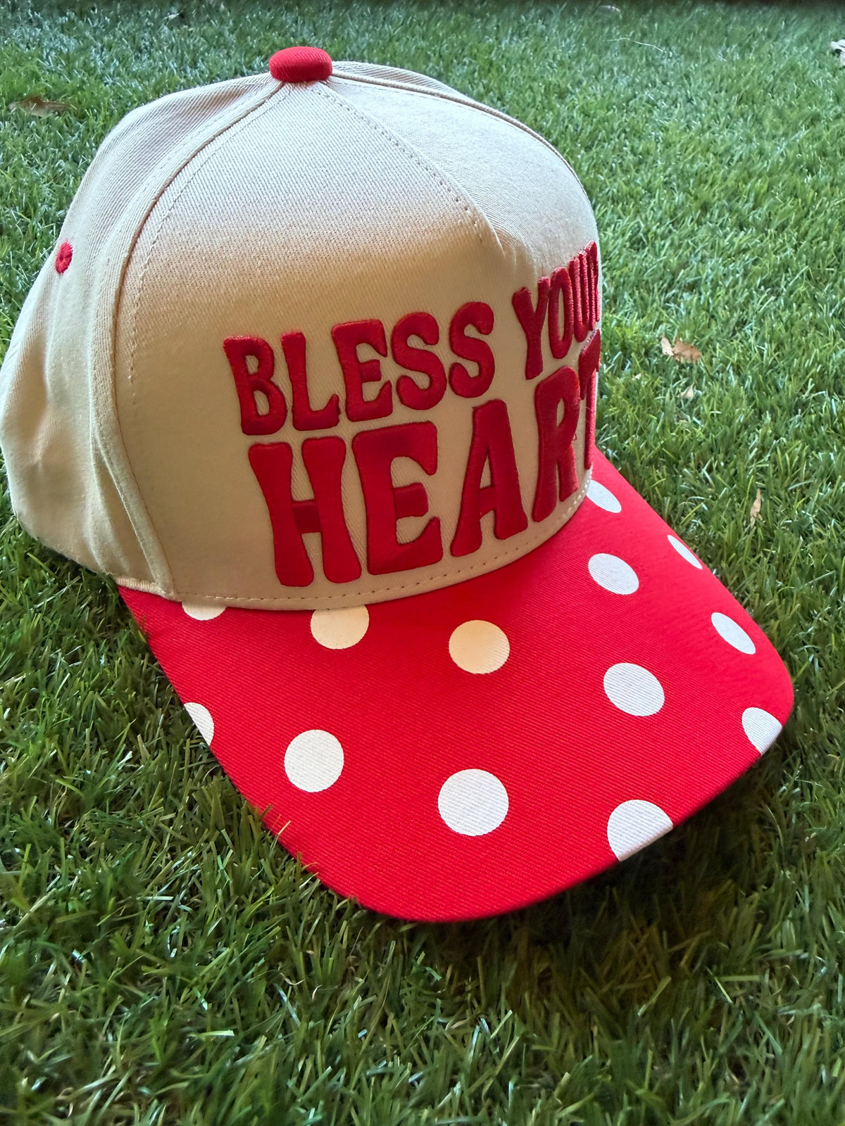 BLESS YOUR HEART embroidered word patch on a custom canvas trucker hat with red and white polka dot brim